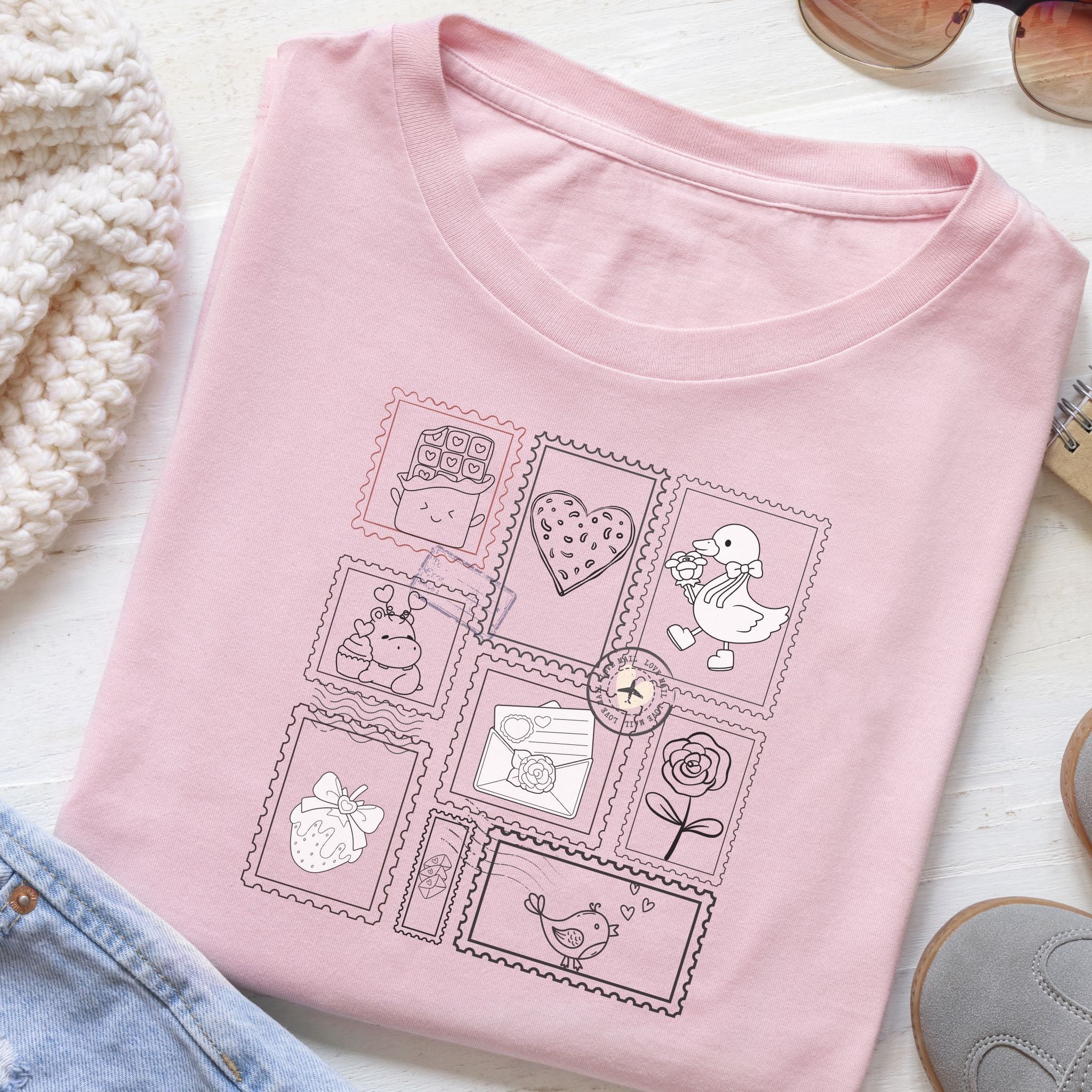 Pink t-shirt with cute illustrations on a light wooden surface